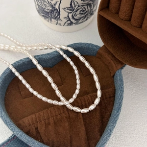 Detail of elegant white pearl necklace presented in a heart-shaped denim jewelry box