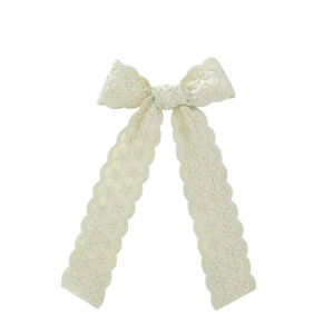 Close-up of cream lace bow hair clip with floral embroidery and scalloped ribbon edge