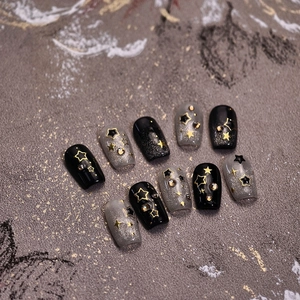 Starry sky themed black and grey press-on nails with gold stars and glitter
