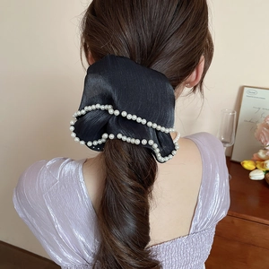 Elegant black satin bow scrunchie with pearl trim worn on long hair shown from behind