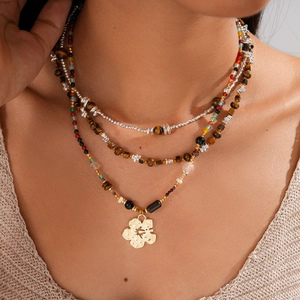Detailed layered bohemian necklace featuring tiger eye beads and gold floral pendant