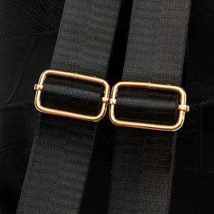 Macro view of adjustable gold-tone buckles on black nylon straps of the commuter backpack