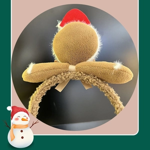 Detail of plush gingerbread man headband with red Santa hat and beige satin ribbon bow