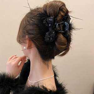 Detail of elegant black hair claw clip featuring shimmering sequins and soft feather accents