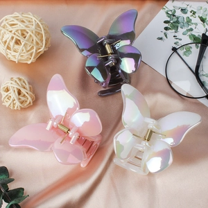 Three holographic butterfly hair claws in purple, pink and white on silk fabric