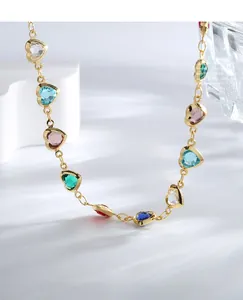 Macro side view of golden heart-shaped necklace featuring vibrant multi-color crystals
