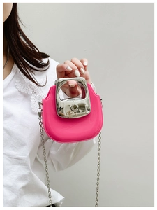 Close-up of a pink PVC jelly bag with a silver metal handle and chain strap worn by a model