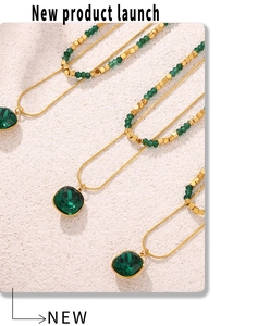 Dettaglio del ciondolo in cristallo verde smeraldo su catena serpente dorata con perle