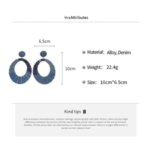 Detail view of large oval denim fabric earrings with size measurements of 10cm by 6.5cm