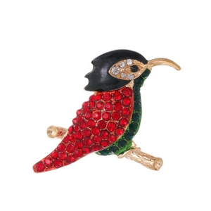 Detail of red rhinestone bird brooch with green enamel on golden tree branch