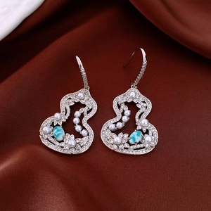 Elegant hulu-shaped pearl earrings with turquoise accents on red silk background