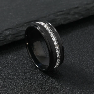 Minimalist black stainless steel ring with single row of square diamonds on stone background