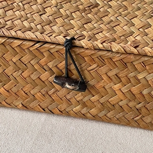 Detailed close-up of natural seagrass weave texture and dark wooden olive buckle closure