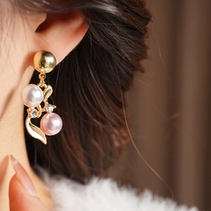 Gros plan d'une boucle d'oreille vintage dorée avec perles blanches, roses et diamant
