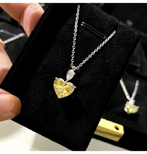Close-up of heart-shaped yellow zircon pendant on a silver chain over black velvet