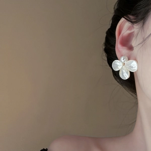 Close-up of elegant French floral pearl earrings worn by a model in soft lighting