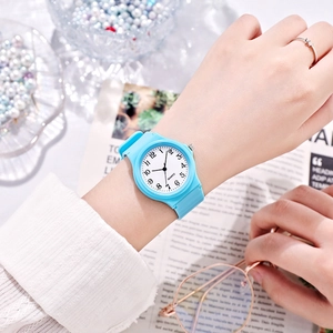 Minimalist round quartz watch with light blue silicone strap shown on a model's wrist