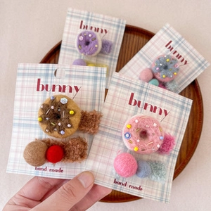 Detail of handmade donut hair clips with colorful beads on a wooden tray background