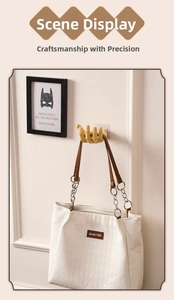 Creative hand-shaped wall hook in gold finish holding a white canvas tote bag