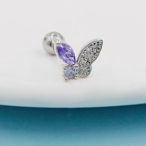 Macro shot of silver butterfly piercing with purple stone and round zircon crystal