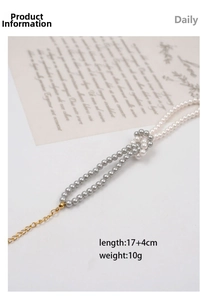 Detail of vintage gray and white pearl necklace with knot design and gold extension chain
