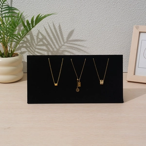 Detail of black velvet jewelry display board with gold necklaces and fortune pendants