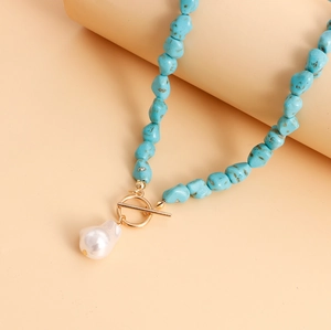Detail of turquoise beaded necklace featuring a white baroque pearl pendant and gold OT clasp