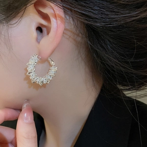 Close-up of minimalist silver hoop earrings with pave set rectangular zircons on model
