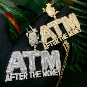Detailed view of gold and silver ATM After The Money iced out pendants for hip hop jewelry