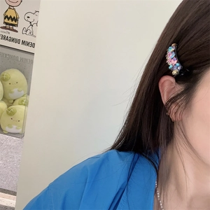 Vue détaillée d'une petite barrette avec strass colorés portée sur les cheveux d'un mannequin