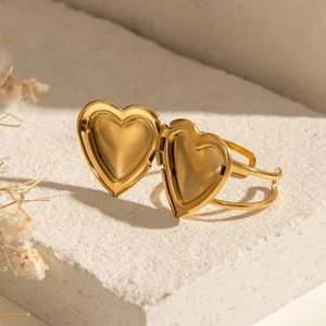 Detailed view of a gold heart locket bracelet on a white stone base with warm lighting