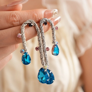 Detail view of vintage woven metal drop earrings with colorful crystals held by hand