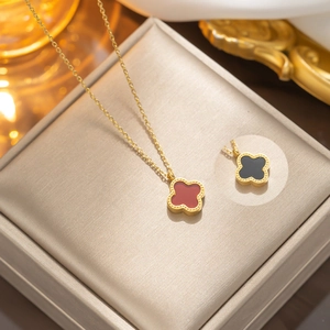 Gold stainless steel clover jewelry set with red and black shell inlay on a jewelry box
