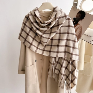 Classic plaid scarf in beige and brown with tassels styled on a matching beige coat