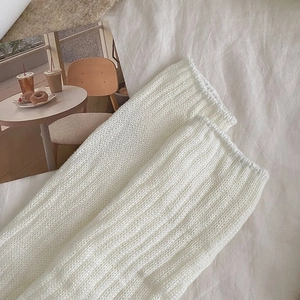 Detail of white cable knit leg warmer with vertical ribbing pattern and soft texture