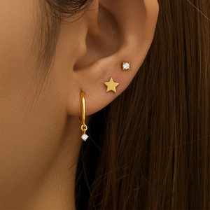 Detailed view of three gold earring set featuring a star stud and zirconia stone charms