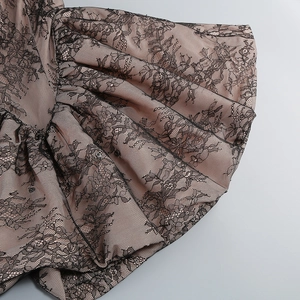 Detailaufnahme von schwarzer Spitze auf rosa Stoff mit gerafften Texturen und Details