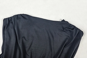Detailed view of black ruched sleeveless V-neck dress featuring sleek textured fabric