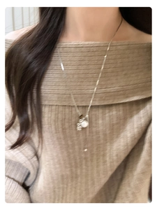 Detail of silver chain necklace with tiger eye stone and pearl pendant on a model