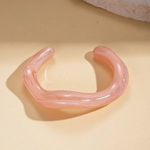 Macro shot of pink marble acrylic cuff bracelet featuring wave-like irregular geometry