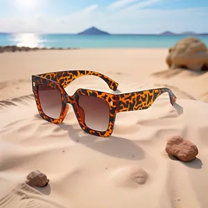 Square tortoise shell sunglasses with brown gradient lenses on a sunny beach setting