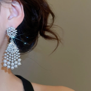 Close-up of vintage pearl drop earrings with rhinestones on model showing scale