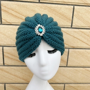 Winter knitted headwrap in dark teal with ornate silver flower and blue gemstone detail