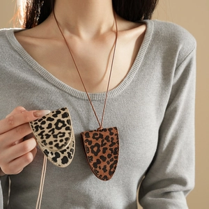 Detail of leopard print faux leather glasses case necklaces in brown and cream colors