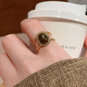 Close-up of 18k gold plated tiger eye ring worn on hand holding a coffee cup