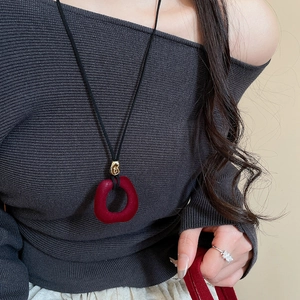 Detail view of a long necklace with a red velvet ring pendant and a golden metal clasp