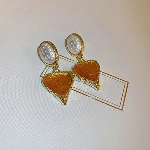 Detail of vintage heart earrings with gold textured metal frames and orange resin