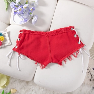 Dettaglio di pantaloncini in denim rosso con lacci laterali e bordi sfrangiati su divano