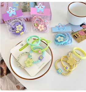 Flat lay of colorful candy-toned floral hair ties with beads and elastic bands on a white tray