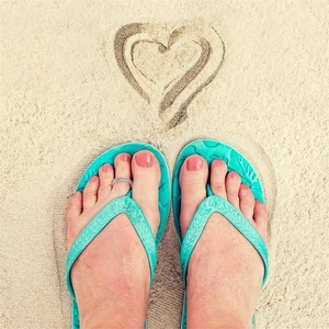 Detailed view of an S925 sterling silver toe ring worn with blue beach flip-flops